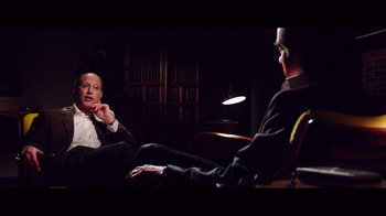 Movie still from “20,000 Days on Earth” (2014), directed by Iain Forsyth – Two men are sitting in a dark room; Medium shot, Over the shoulder angle