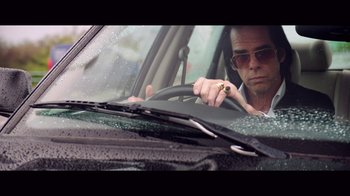 Movie still from “20,000 Days on Earth” (2014), directed by Iain Forsyth – A man driving a car while smoking a cigarette; Medium shot, Low angle