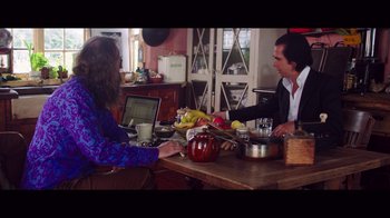 Movie still from “20,000 Days on Earth” (2014), directed by Iain Forsyth – Two people sitting at a table with a laptop; Medium shot, Over the shoulder angle