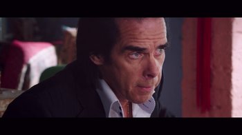 Movie still from “20,000 Days on Earth” (2014), directed by Iain Forsyth – A man in a suit and tie looking to his left; Close Up shot, Over the shoulder angle