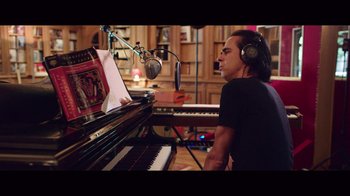 Movie still from “20,000 Days on Earth” (2014), directed by Iain Forsyth – A man wearing headphones sitting in front of a grand piano; Medium shot, High angle