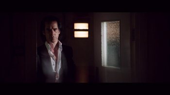 Movie still from “20,000 Days on Earth” (2014), directed by Iain Forsyth – A man standing in a dark room smoking a cigarette; Medium shot, Low angle
