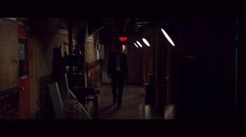 Movie still from “20,000 Days on Earth” (2014), directed by Iain Forsyth – A man walking down a hallway in a dark room; Wide shot, Low angle