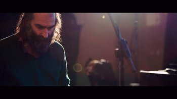 Movie still from “20,000 Days on Earth” (2014), directed by Iain Forsyth – A man with long hair and a goatee standing in front of a microphone; Medium shot, Low angle
