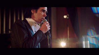 Movie still from “20,000 Days on Earth” (2014), directed by Iain Forsyth – A man in a black jacket is holding a microphone; Close Up shot, Low angle