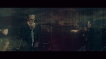 Movie still from “20,000 Days on Earth” (2014), directed by Iain Forsyth – A man in a suit and tie holding a cell phone to his ear; Medium shot, Low angle