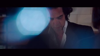 Movie still from “20,000 Days on Earth” (2014), directed by Iain Forsyth – A person wearing a suit and tie; Close Up shot, Over the shoulder angle