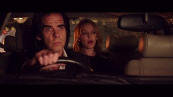 Movie still from “20,000 Days on Earth” (2014), directed by Iain Forsyth – A man and a woman in the back seat of a car; Medium shot, Over the shoulder angle