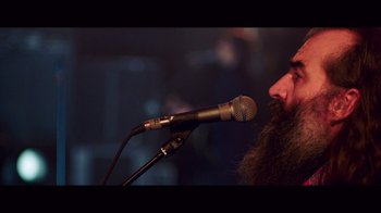 Movie still from “20,000 Days on Earth” (2014), directed by Iain Forsyth – A man with a long beard is speaking into a microphone; Close Up shot, Low angle