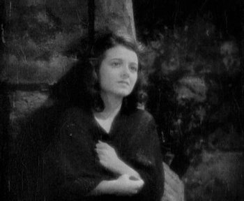 Movie still from “7th Heaven” (1927), directed by Frank Borzage – A woman standing next to a tree in a black and white photo; Medium shot, High angle