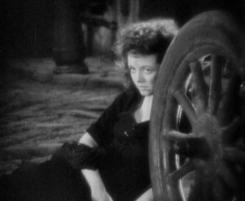 Movie still from “7th Heaven” (1927), directed by Frank Borzage – A woman sitting next to a wheel in a black and white photo; Medium shot, High angle