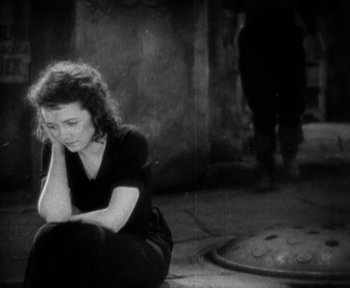 Movie still from “7th Heaven” (1927), directed by Frank Borzage – A woman sitting on the ground with her arms folded on her knees; Medium shot, High angle
