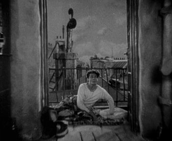 Movie still from “7th Heaven” (1927), directed by Frank Borzage – A man sitting on the ground on a balcony; Wide shot, High angle