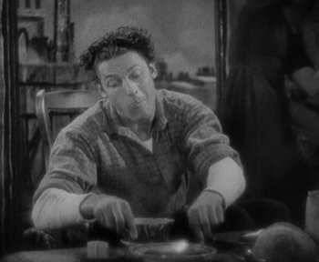 Movie still from “7th Heaven” (1927), directed by Frank Borzage – A man sitting at a table with a plate in front of him; Medium shot, High angle