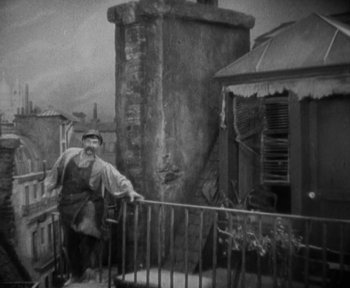 Movie still from “7th Heaven” (1927), directed by Frank Borzage – An older man standing on a balcony with a pipe; Wide shot, High angle