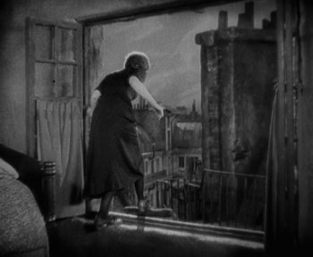 Movie still from “7th Heaven” (1927), directed by Frank Borzage – An older woman standing in front of an open window; Wide shot, Low angle