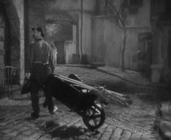 Movie still from “7th Heaven” (1927), directed by Frank Borzage – A man walking down a street with a cart of wood; Wide shot, High angle