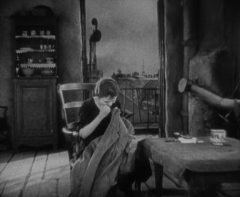 Movie still from “7th Heaven” (1927), directed by Frank Borzage – A woman sitting in a chair in a living room; Medium shot, High angle