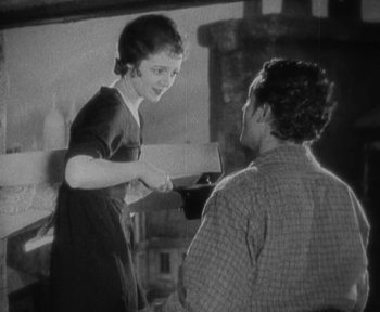 Movie still from “7th Heaven” (1927), directed by Frank Borzage – An old photo of a woman shaking a man's hand in front of a fireplace; Medium shot, Low angle