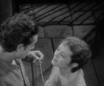 Movie still from “7th Heaven” (1927), directed by Frank Borzage – A man and a woman are holding a string together; Close Up shot, High angle