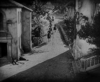 Movie still from “7th Heaven” (1927), directed by Frank Borzage – A black and white photo of people riding horses down a street; Extreme Wide shot, High angle