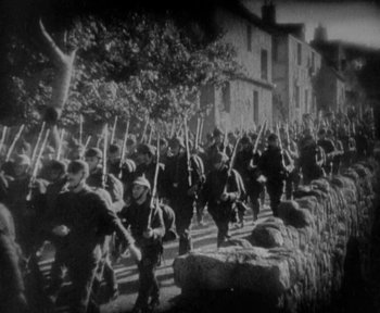 Movie still from “7th Heaven” (1927), directed by Frank Borzage – A black and white photo of a group of soldiers marching down a street; Wide shot, High angle
