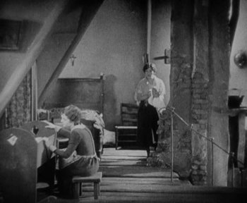 Movie still from “7th Heaven” (1927), directed by Frank Borzage – A man sitting on a chair next to a woman; Wide shot, High angle