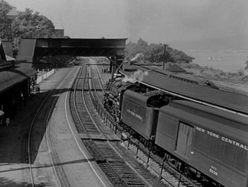 Movie still from “A Letter to Three Wives” (1949), directed by Joseph L. Mankiewicz – An old black and white photo of a train going down the tracks; Extreme Wide shot, High angle