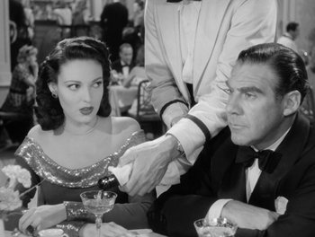 Movie still from “A Letter to Three Wives” (1949), directed by Joseph L. Mankiewicz – An old photo of a man and a woman sitting at a dinner table; Medium shot, Over the shoulder angle