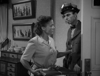 Movie still from “A Letter to Three Wives” (1949), directed by Joseph L. Mankiewicz – An old photo of a man and a woman holding a gift; Medium shot, High angle