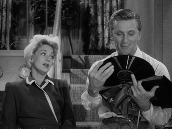 Movie still from “A Letter to Three Wives” (1949), directed by Joseph L. Mankiewicz – A man and a woman are looking at a cd; Medium shot, Over the shoulder angle