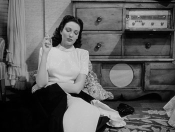 Movie still from “A Letter to Three Wives” (1949), directed by Joseph L. Mankiewicz – A black and white photo of a woman smoking a cigarette; Medium shot, High angle