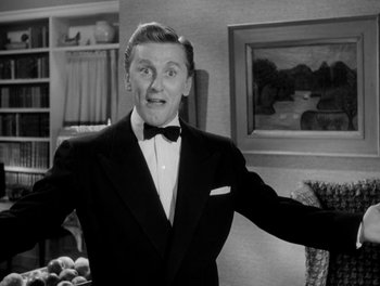 Movie still from “A Letter to Three Wives” (1949), directed by Joseph L. Mankiewicz – A man in a suit and bow - tie standing in front of a painting; Medium shot, Low angle