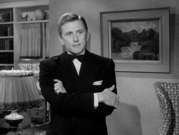 Movie still from “A Letter to Three Wives” (1949), directed by Joseph L. Mankiewicz – A man in a suit standing with his arms crossed; Medium shot, Low angle