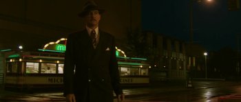 Movie still from “A Prairie Home Companion” (2006), directed by Robert Altman – A man in a suit and hat standing in front of a diner; Medium shot, Low angle