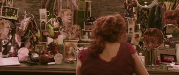 Movie still from “A Prairie Home Companion” (2006), directed by Robert Altman – A woman looking in the mirror in front of a mirror; Medium shot, Over the shoulder angle