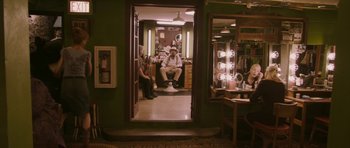 Movie still from “A Prairie Home Companion” (2006), directed by Robert Altman – A man sitting in a barber chair in front of a mirror; Wide shot, High angle