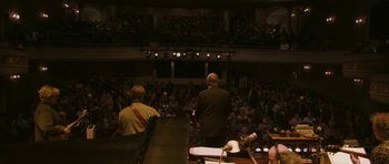 Movie still from “A Prairie Home Companion” (2006), directed by Robert Altman – Two men are standing in front of an audience; Extreme Wide shot, High angle