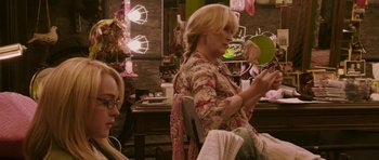Movie still from “A Prairie Home Companion” (2006), directed by Robert Altman – A woman sitting in front of a mirror looking at her phone; Medium shot, Over the shoulder angle