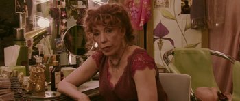 Movie still from “A Prairie Home Companion” (2006), directed by Robert Altman – A woman in a red dress sitting in front of a mirror; Close Up shot, High angle