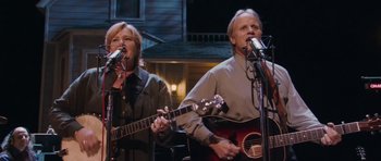 Movie still from “A Prairie Home Companion” (2006), directed by Robert Altman – A man and a woman sing into microphones; Medium shot, High angle