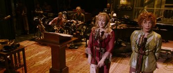 Movie still from “A Prairie Home Companion” (2006), directed by Robert Altman – A woman standing in front of microphones in a room; Wide shot, High angle