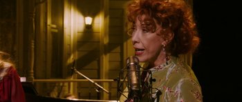 Movie still from “A Prairie Home Companion” (2006), directed by Robert Altman – A woman with red curly hair singing into a microphone; Close Up shot, Low angle