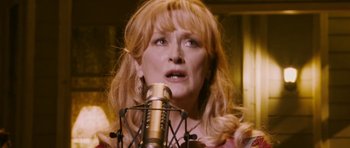 Movie still from “A Prairie Home Companion” (2006), directed by Robert Altman – A person singing on a microphone; Close Up shot, Low angle