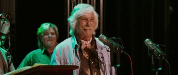 Movie still from “A Prairie Home Companion” (2006), directed by Robert Altman – An older man with long white hair standing in front of a microphone; Close Up shot, Low angle