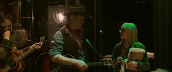 Movie still from “A Prairie Home Companion” (2006), directed by Robert Altman – A man and a woman are playing a guitar; Medium shot, Over the shoulder angle