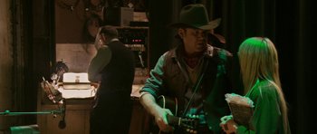 Movie still from “A Prairie Home Companion” (2006), directed by Robert Altman – A man in a cowboy hat playing a guitar; Medium shot, Over the shoulder angle