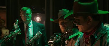 Movie still from “A Prairie Home Companion” (2006), directed by Robert Altman – A man in a cowboy hat is talking into a microphone; Medium shot, Low angle