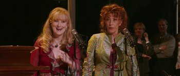Movie still from “A Prairie Home Companion” (2006), directed by Robert Altman – A couple of women standing next to each other; Medium shot, High angle