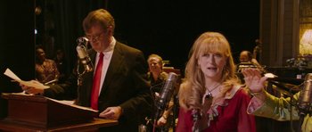 Movie still from “A Prairie Home Companion” (2006), directed by Robert Altman – A man and a woman in a red dress; Medium shot, Over the shoulder angle